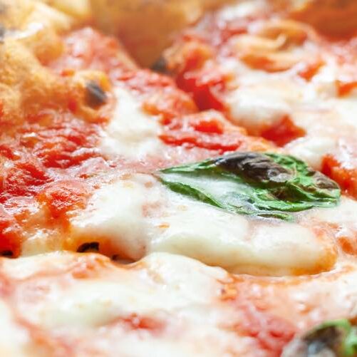 Close up of slices of pizza margherita with basil.